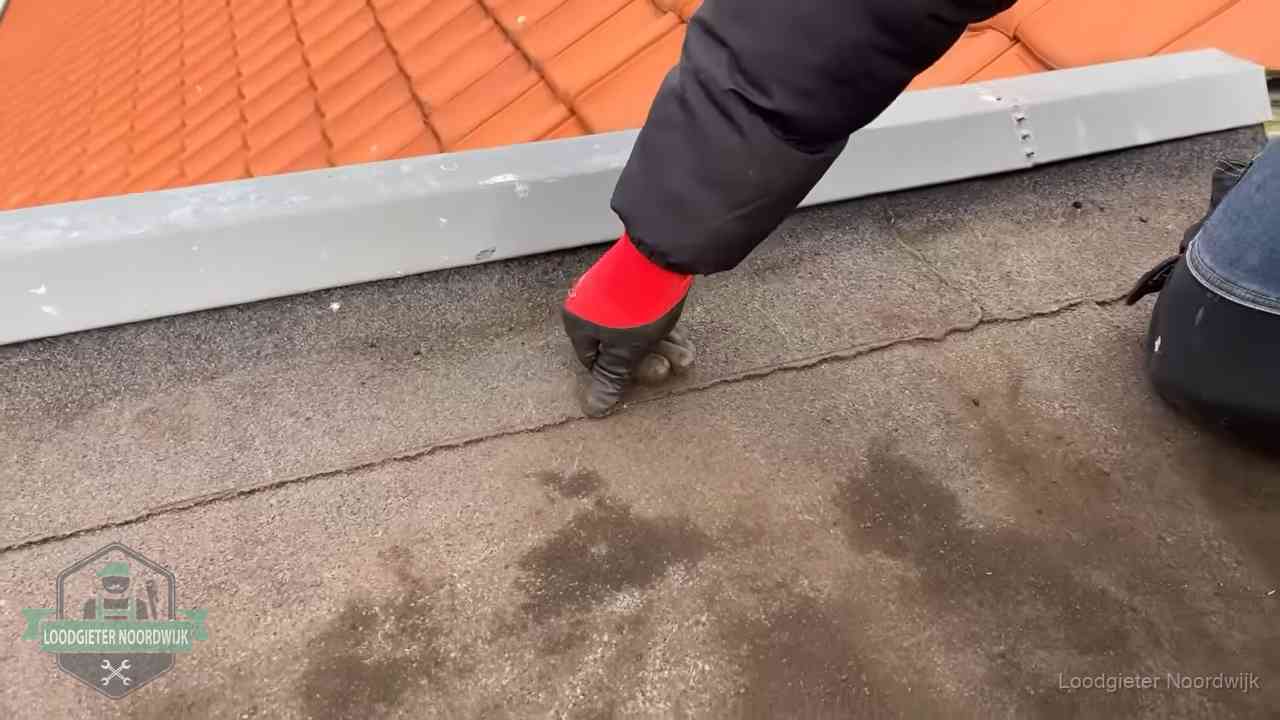Lekkage bij de naad van een plat dak in Noordwijk Vakman wijst een naad met vochtplekken aan op een bitumen plat dak in Noordwijk