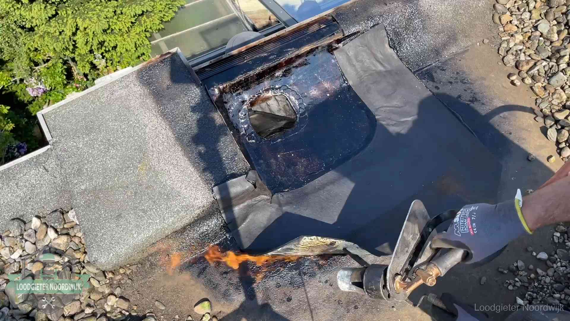 Daklekkage repareren in Noordwijk Dakdekker brandt bitumen rond een doorvoer tijdens een daklekkage-reparatie in Noordwijk