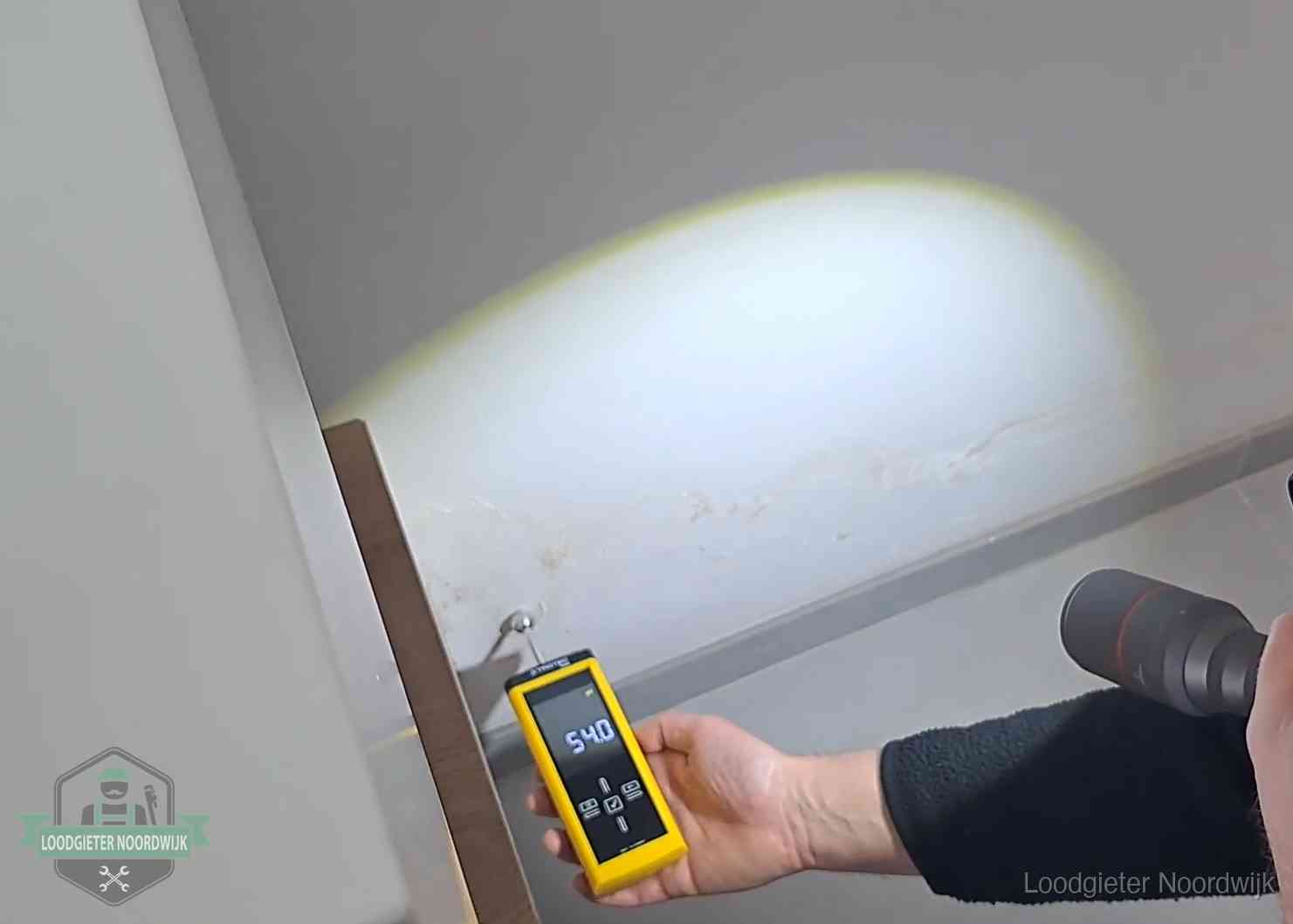 Vochtmeter tegen een natte wand met lekkagesporen in Noordwijk