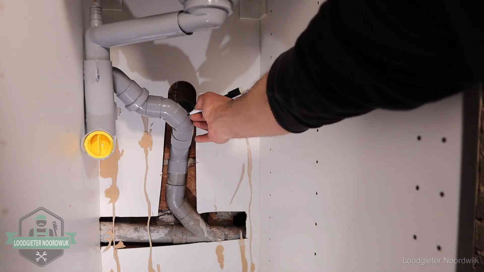 Loodgieter markeert een pvc-afvoerbuis onder een gootsteen in Noordwijk