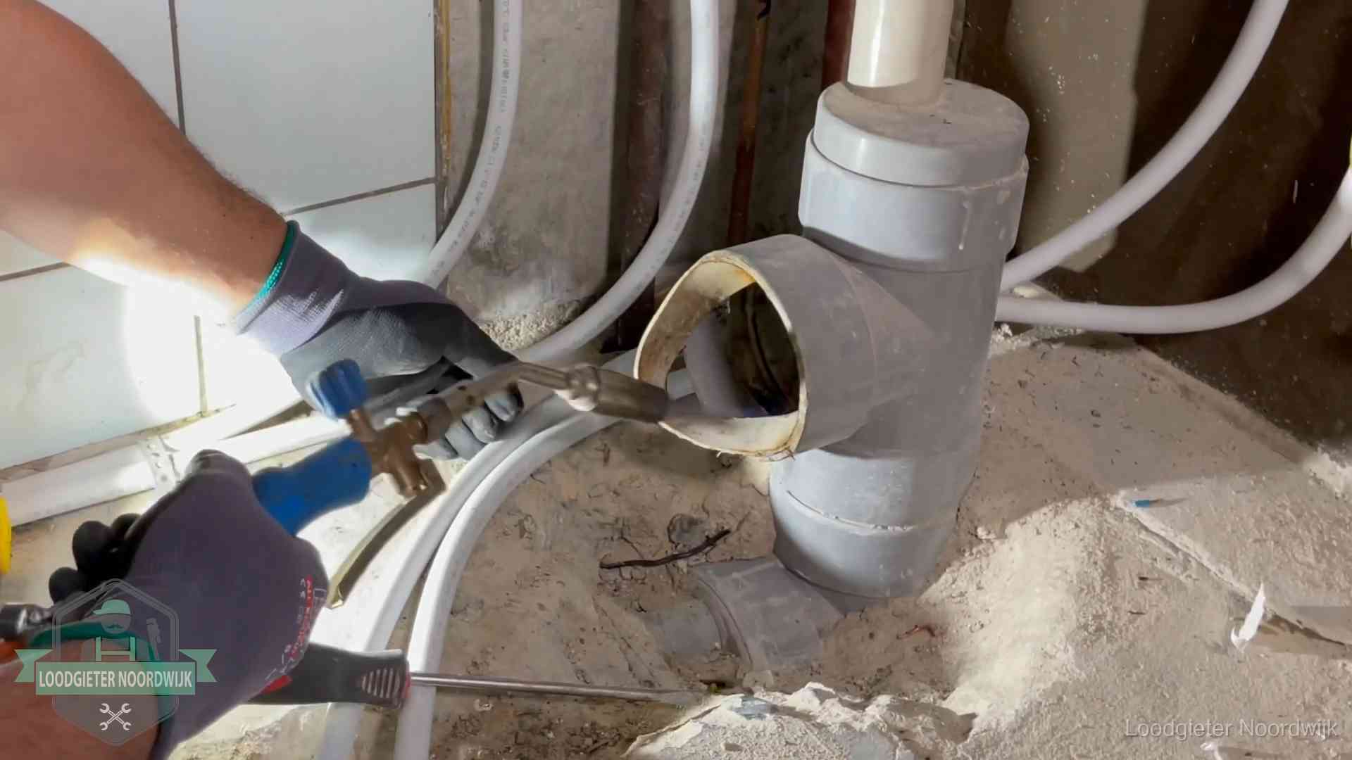 Loodgieter werkt met brander en messing kraanwerk aan leidingen in Noordwijk