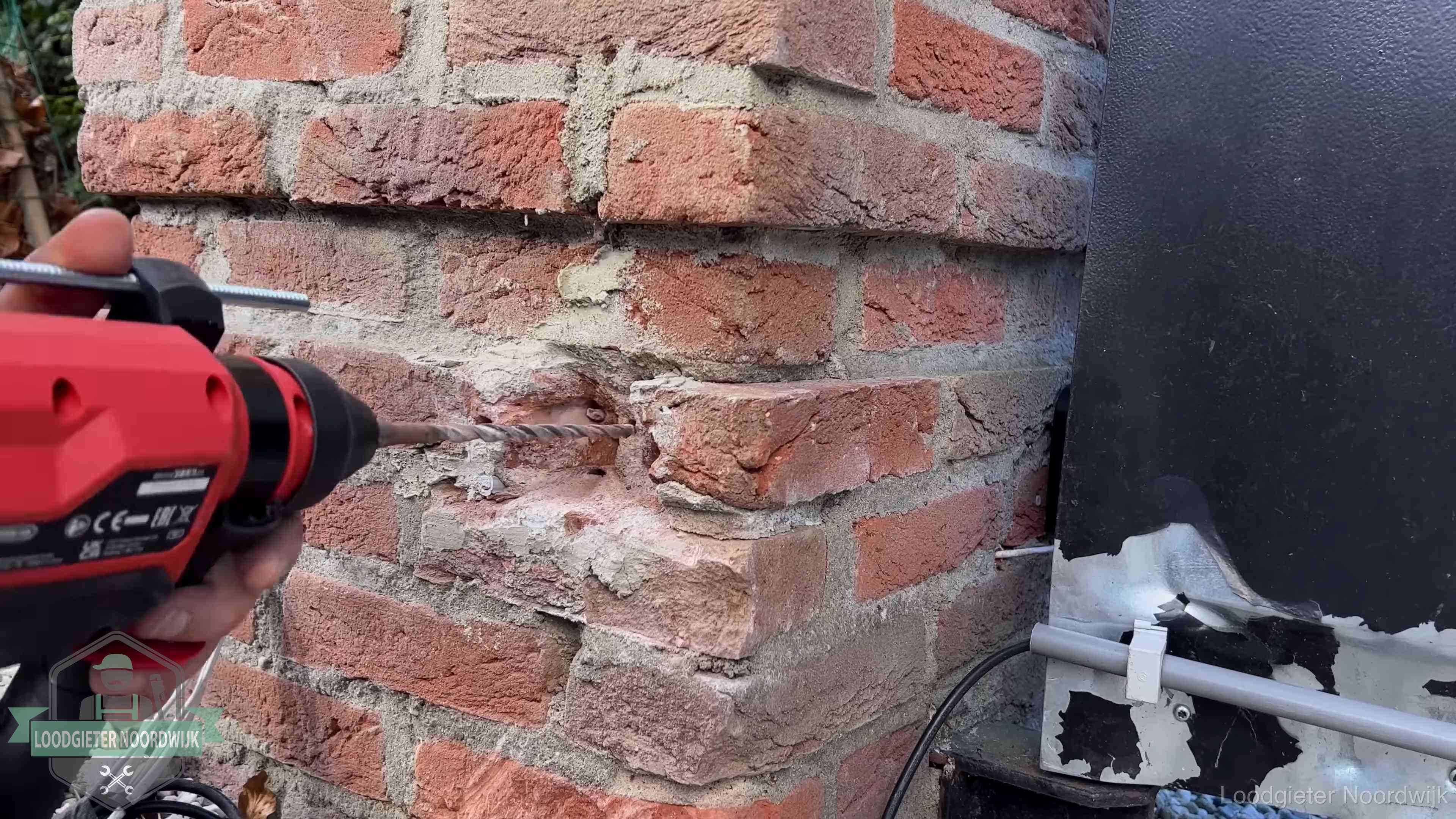 Vakman boort in de buitenmuur van een woning in de regio Noordwijk