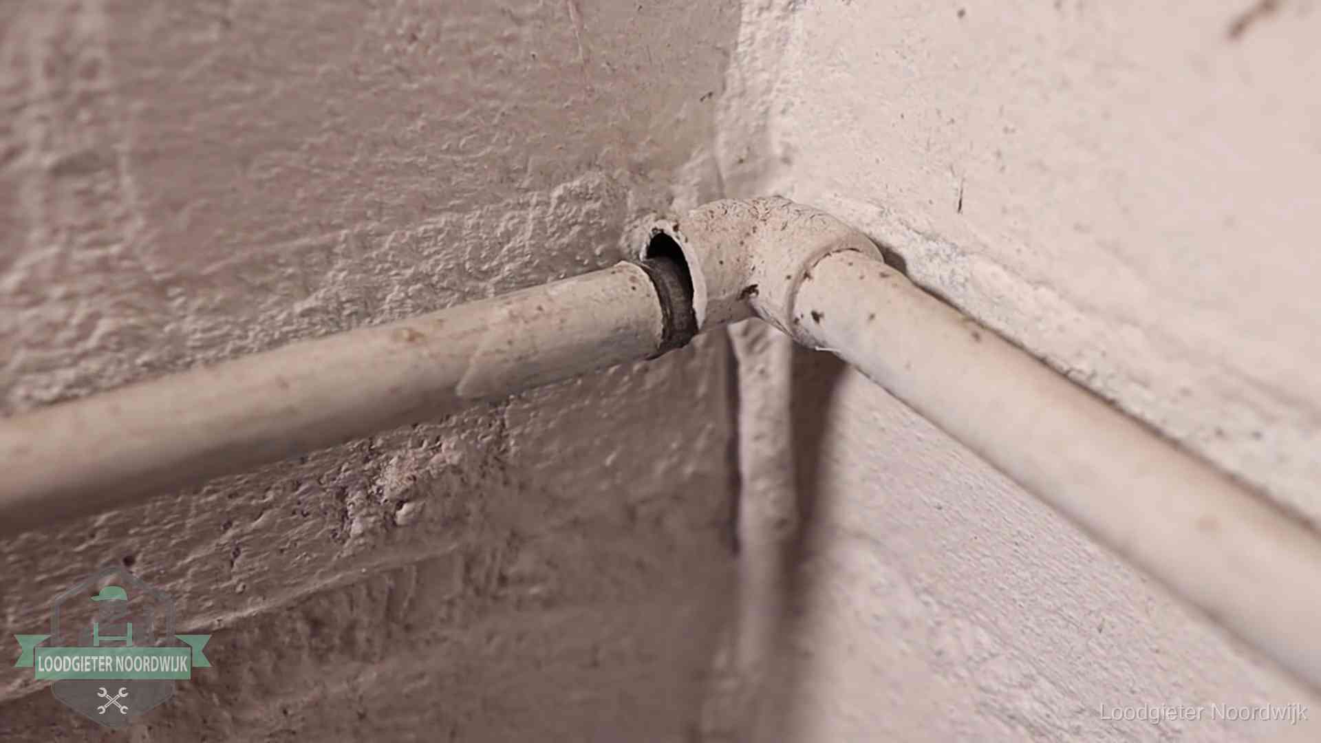 Oude geverfde waterleiding met een losliggende fitting in een woning in Noordwijk