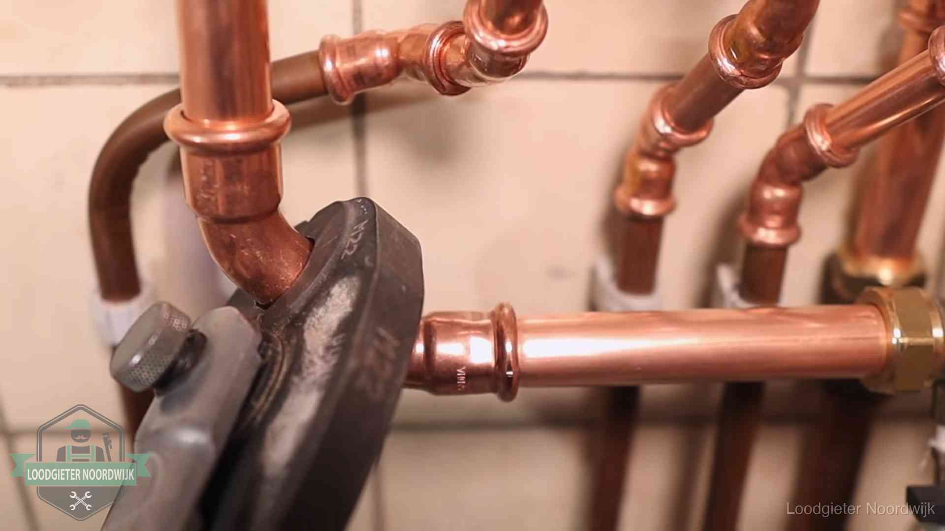 Persmachine perst een koperen fitting op nieuw leidingwerk in Noordwijk