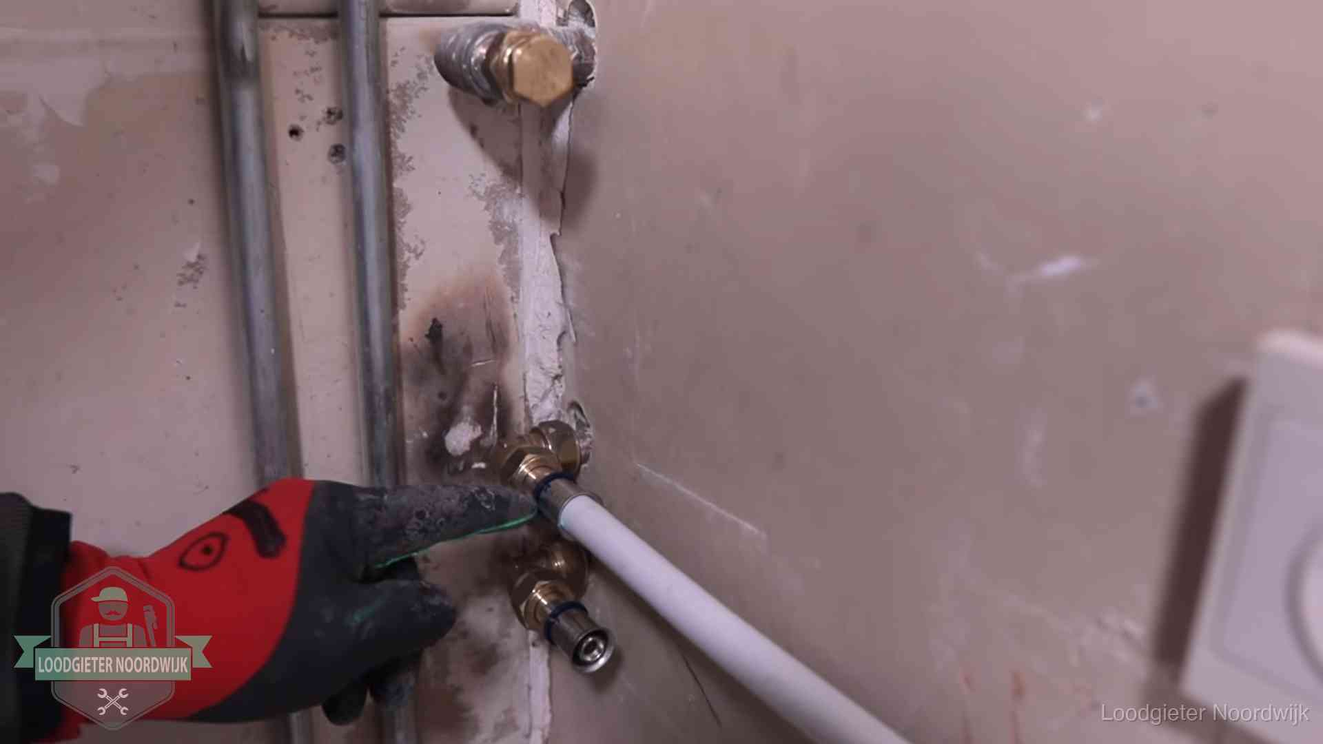Loodgieter wijst de persfitting op nieuwe muuraansluitingen aan in een woning in Noordwijk