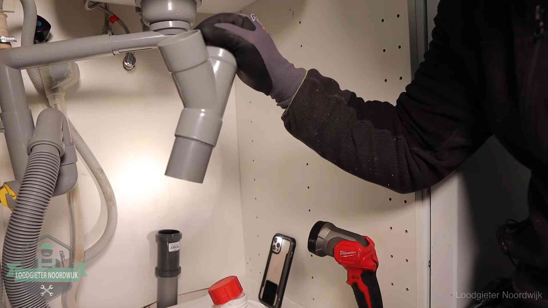 Loodgieter demonteert het sifon- en afvoerwerk onder een gootsteen in Noordwijk bij stankklachten