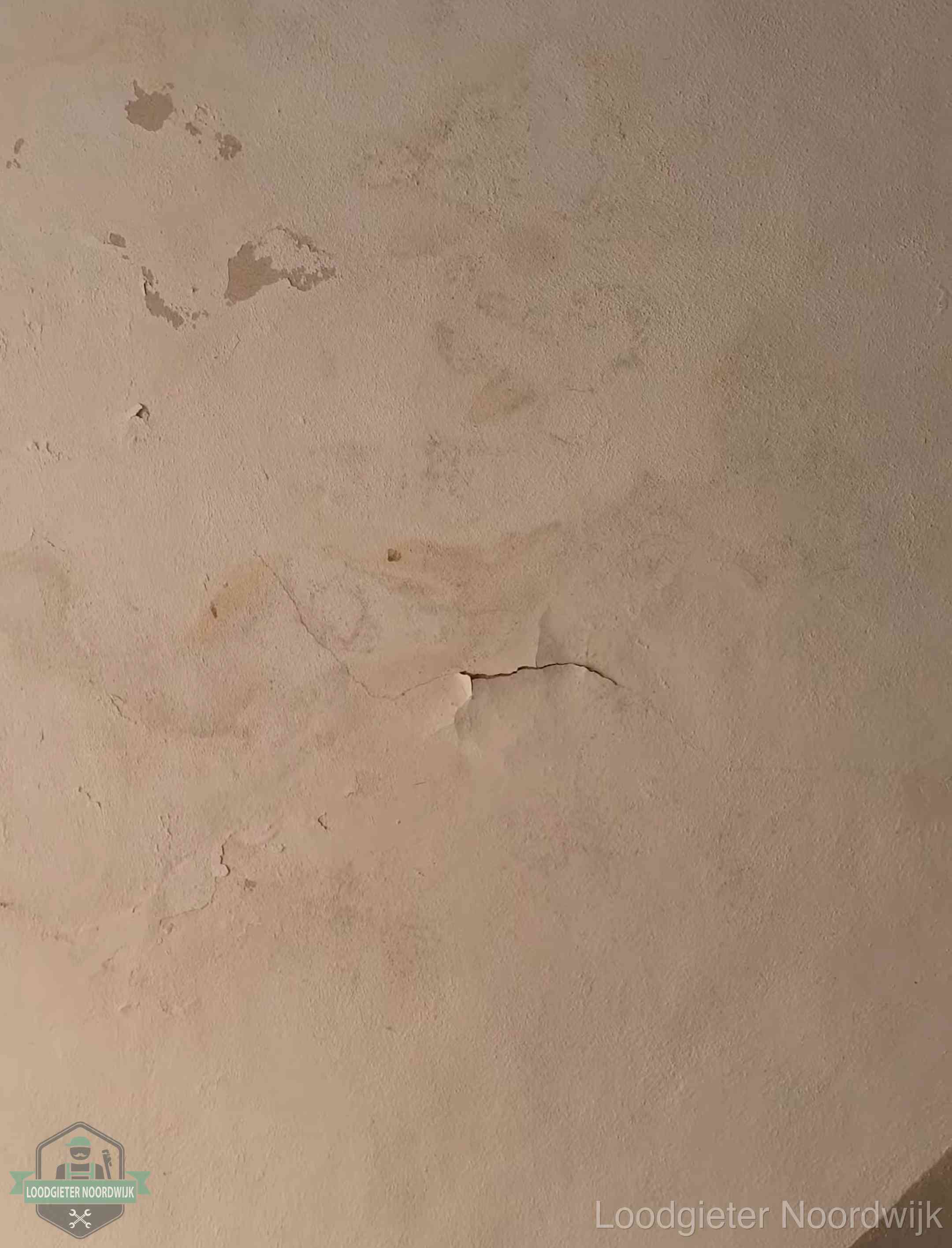 Vochtkringen en afbladderende verf op een plafond in Noordwijk, schade voor het meetrapport en de verzekering